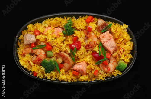 Rice with seafoods on a stone plate over dark background