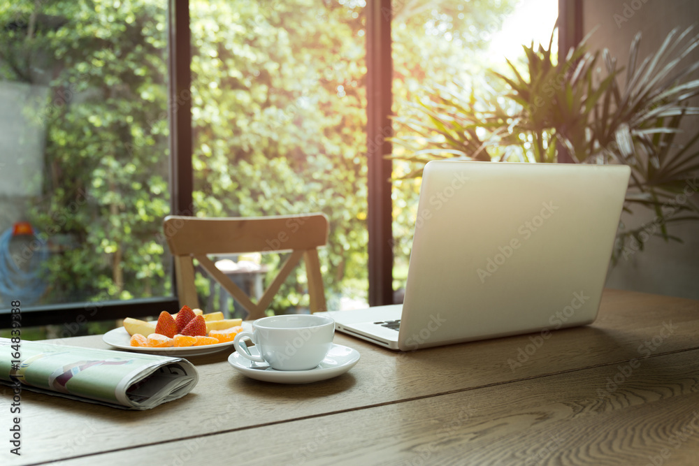 Cup of coffee and fresh fruit with newspaper on the table and laptop computer Cup of coffee and fresh fruit with newspaper on the table and laptop computer