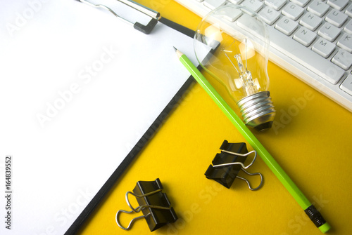 idea light bulb on keyboard and pencil with clip and paper folder and colorful background