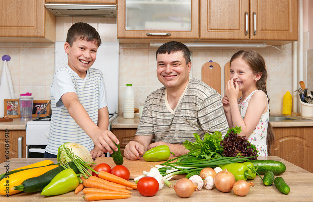 Father and two children in home kitchen interior. Happy family, girl and boy having fun with fruits and vegetables. Healthy food concept. Father and two children in home kitchen interior. Happy family, girl and boy having fun with fruits and vegetables. Healthy food concept.