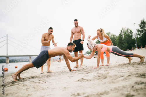 Group of young attractive people having fun on beach and doing some fitness workout. 