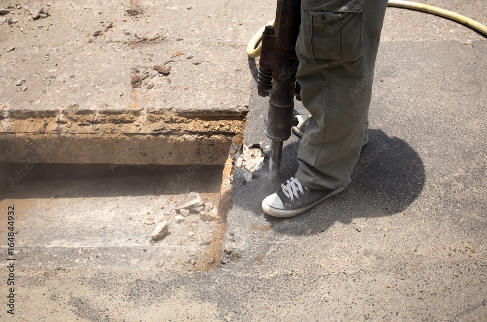 Worker working on the road demolishing asphalt with pneumatic plugger hammer Worker working on the road demolishing asphalt with pneumatic plugger hammer