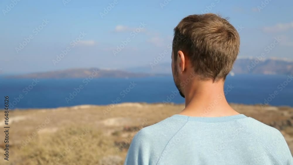 Man enjoying freedom of his being looking at magic landscape of Santorini island Man enjoying freedom of his being looking at magic landscape of Santorini island