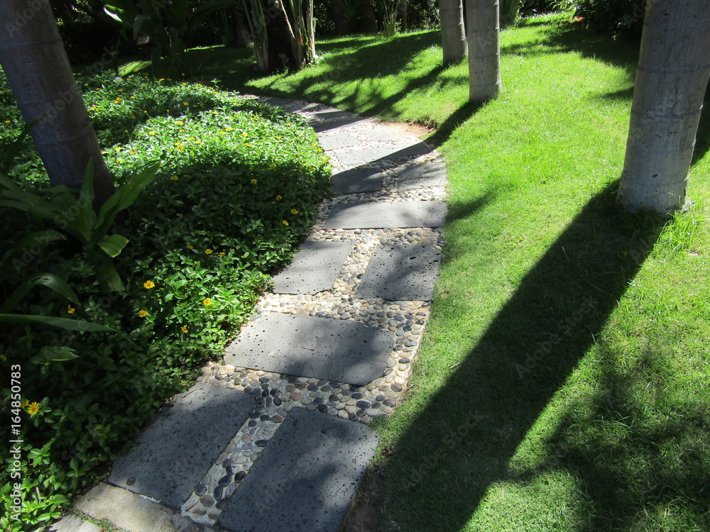 A walking track made of stone slabs among the green grass