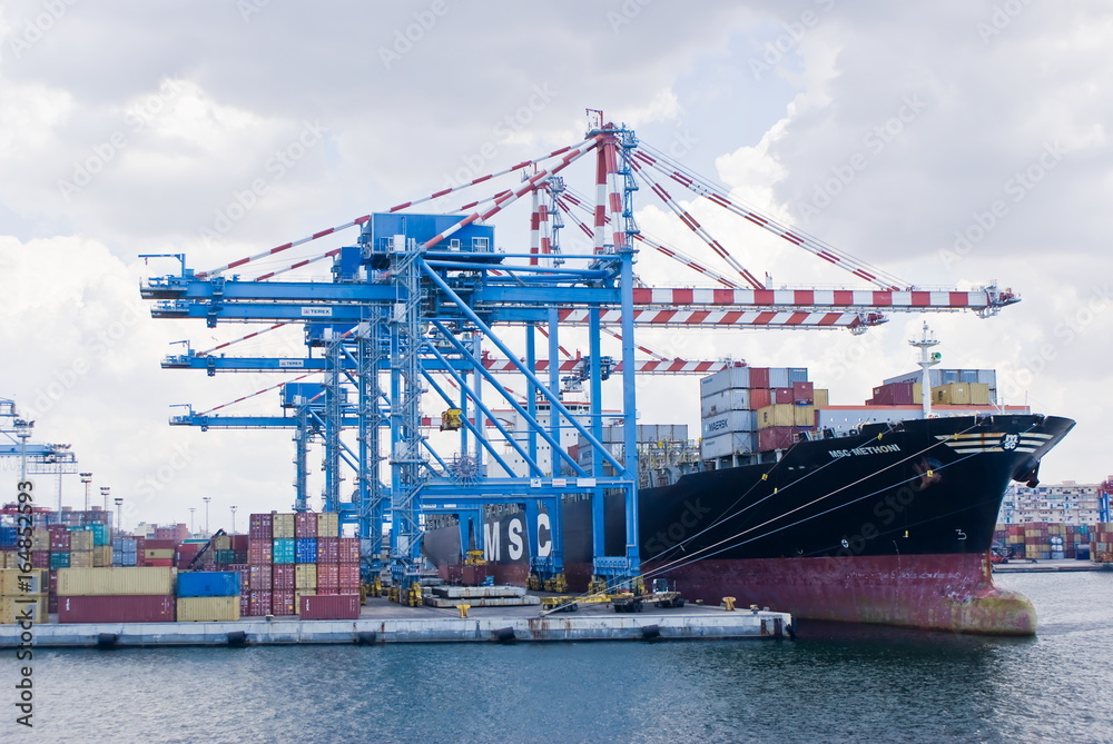 Cranes load a merchant ship in a commercial port terminal, Naples in Italy Cranes load a merchant ship in a commercial port terminal, Naples in Italy