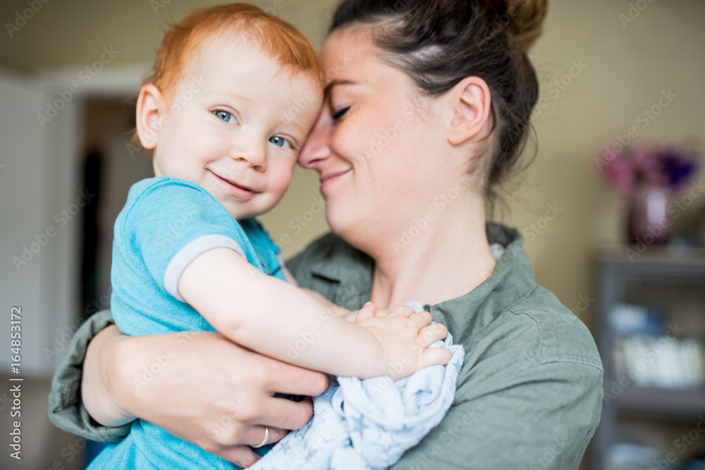 Mutter mit einem rothaarigen Baby auf dem arm und beide lächeln Mutter mit einem rothaarigen Baby auf dem arm und beide lächeln