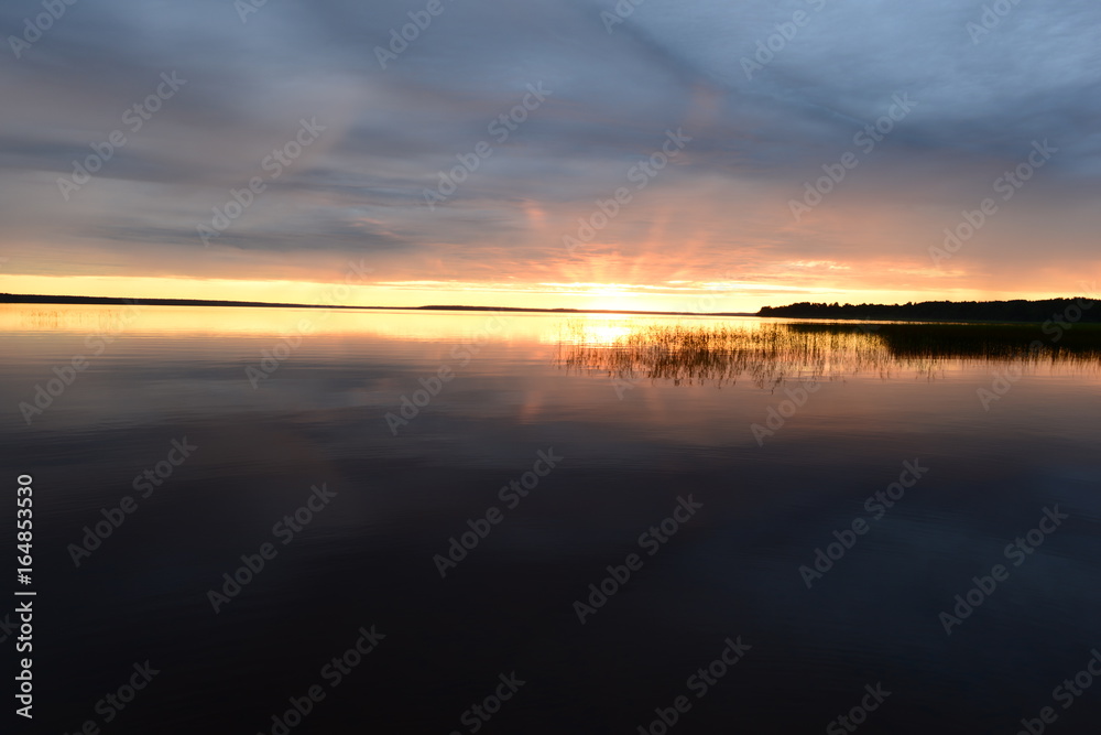 Sun rays at sunset above the water surface