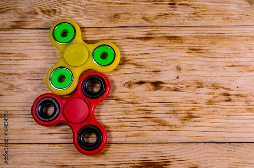 Two fidget spinners on wooden desk. Top view