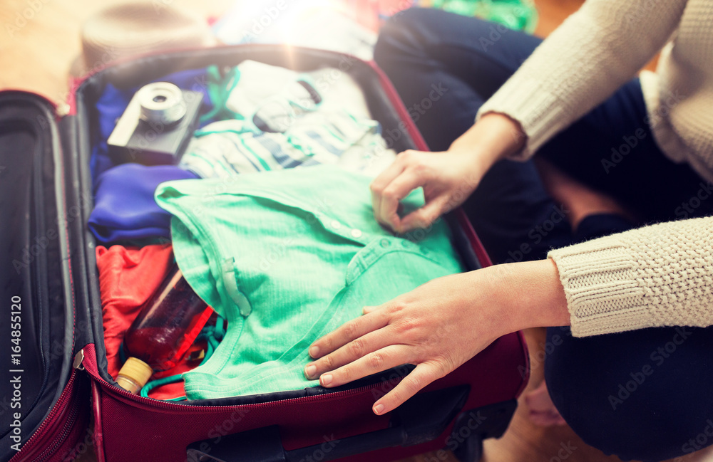 close up of woman packing travel bag for vacation