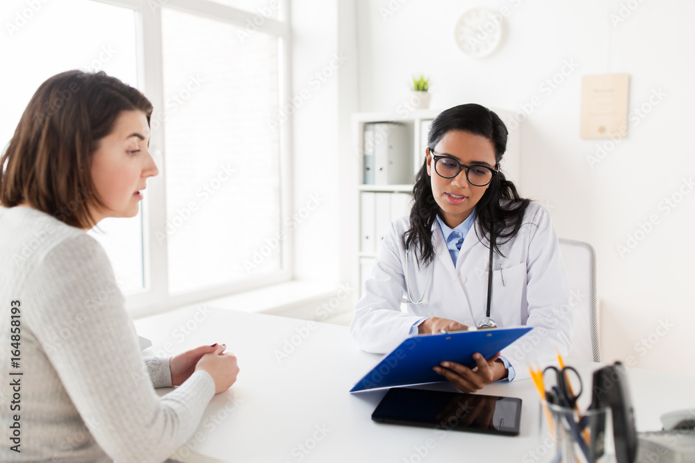 Fototapeta premium doctor with clipboard and woman patient at clinic