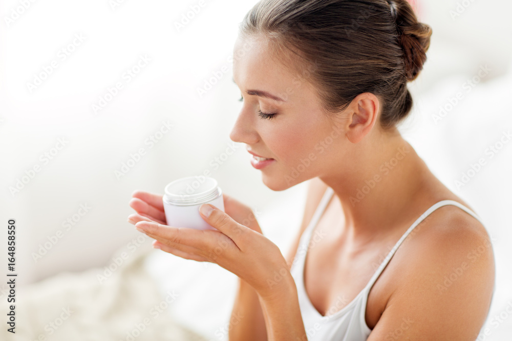 close up of happy woman holding and smelling cream close up of happy woman holding and smelling cream