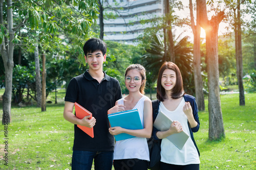 Young Student Asian Group Teenager with school folders on grass at university campus college.