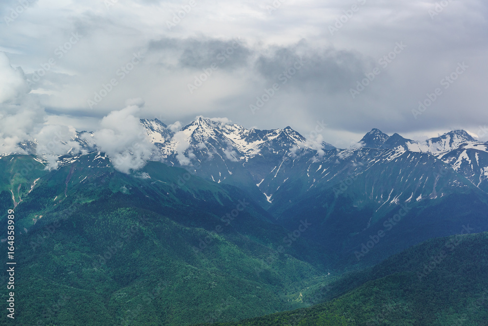 Landscape with snow-covered peaks of the Caucasus mountains and the deep gorge on a summer day