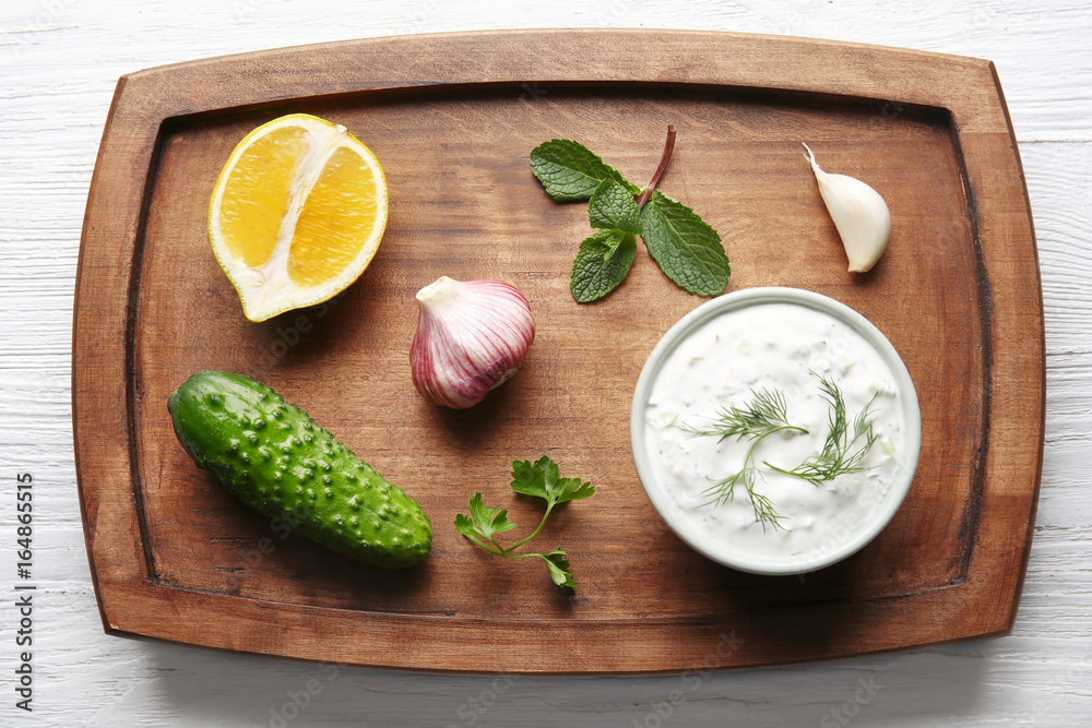 Delicious yogurt sauce in bowl with ingredients on wooden board Delicious yogurt sauce in bowl with ingredients on wooden board