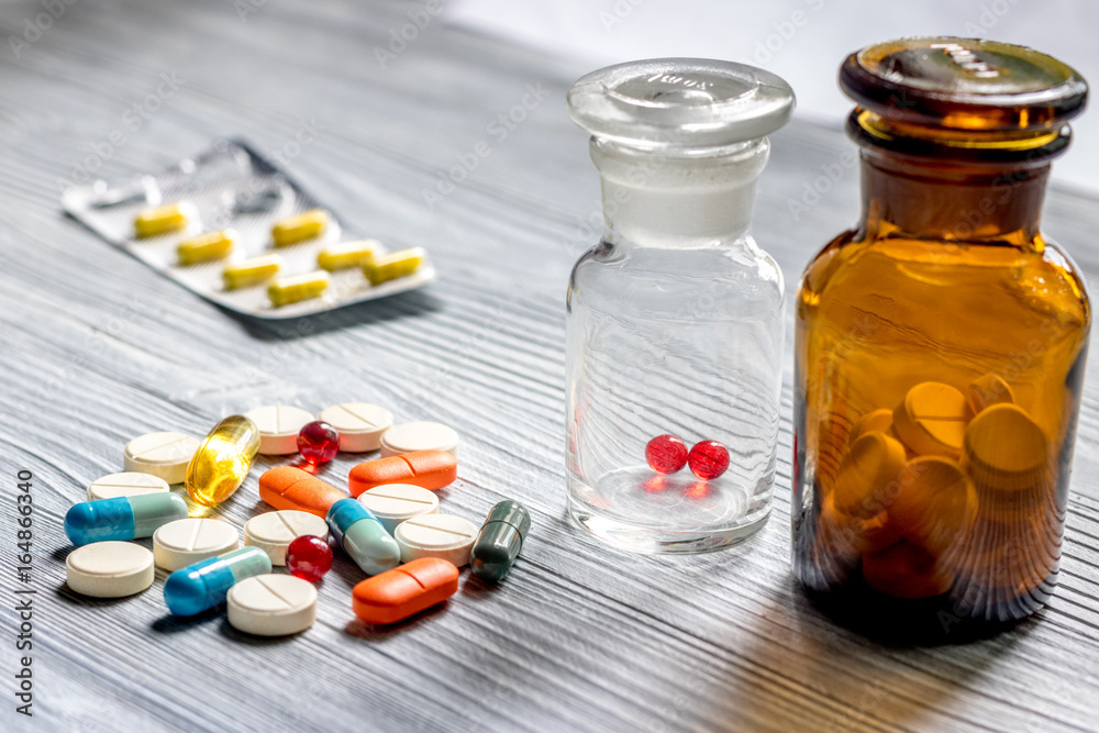 Pills and pill bottle on grey table background Pills and pill bottle on grey table background