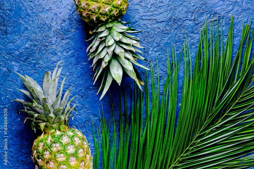 Fototapeta Ananasa i palmy gałąź na błękita stołu tła odgórnego widoku copyspace