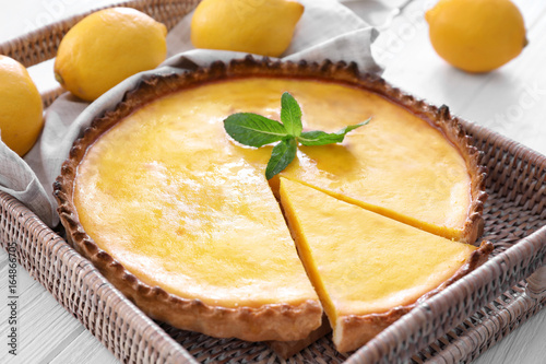 Wicker tray with delicious lemon pie on wooden table, closeup