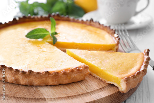 Wooden plate with delicious lemon pie on table, closeup