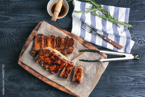 Board with delicious pork ribs on wooden table