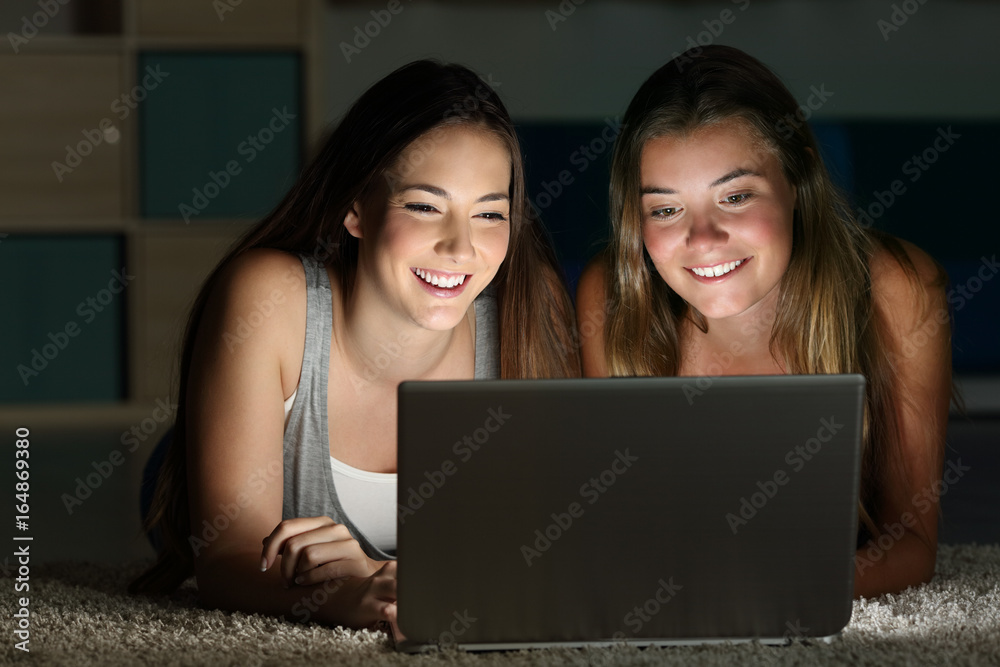 Two teens watching on line content in a laptop