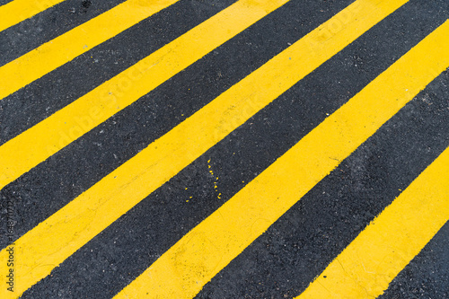 Asphalt Background with diagonal black and yellow warning stripes © Nawadoln