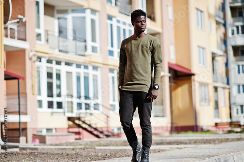 Handsome and attractive african american man posing next to the tall building on a street.