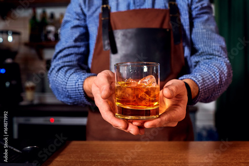 Hands of a bartender at bar restaurant with glass whiskey