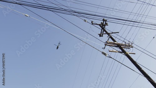 Low angle, helicopter flies over telephone wires photo