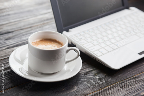 Coffee cup and laptop  on wooden table