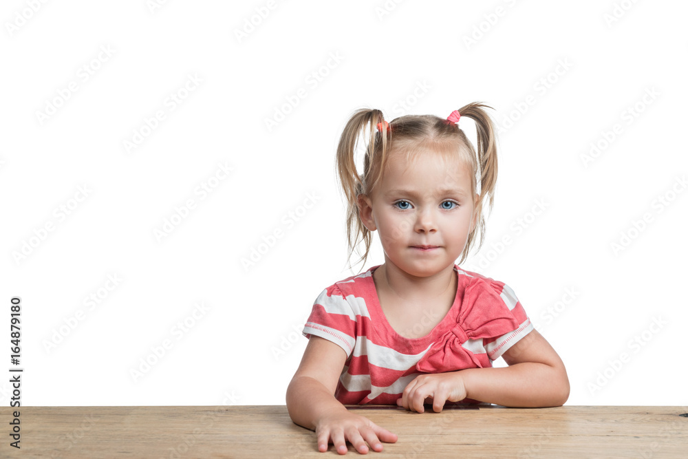 Little beautiful girl sitting at a wooden table isolated on a white background Little beautiful girl sitting at a wooden table isolated on a white background