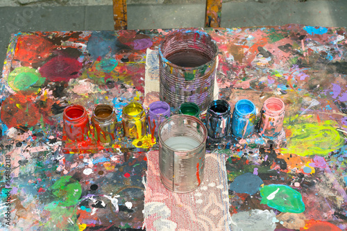 La mesa está llena de colores y envases para pintar.