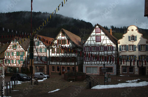 Fachwerk houses, cloudy background, Narrenzunft decorations. Hill covered with fur-grove at the background. Schiltach, Germany