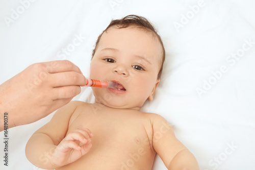 Mother using special syringe to give medicine to her child at home. Health care concept