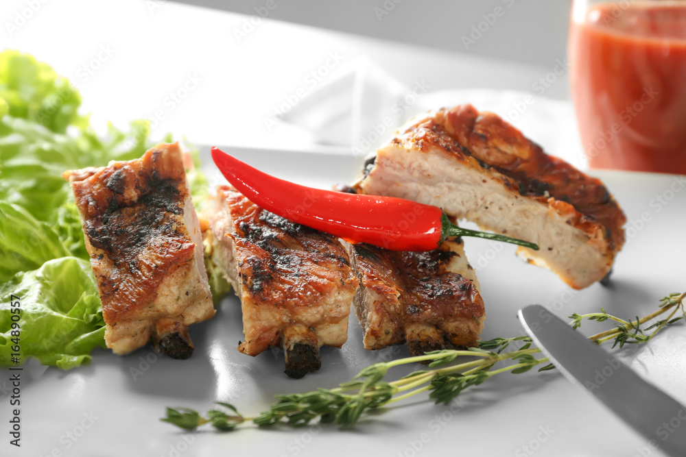 Delicious grilled sliced spare ribs with salad leaves and pepper on white plate