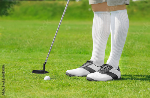 Legs of young man playing golf on course in sunny day
