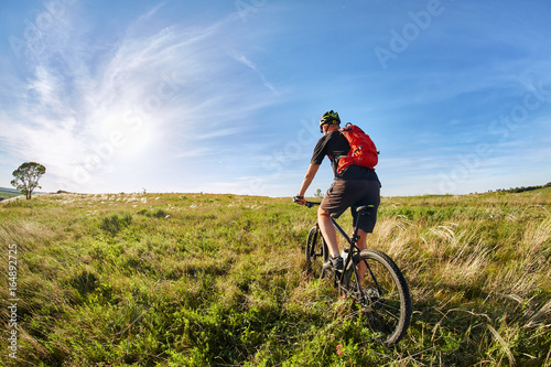 Traveler with backpack Riding the Bike on the Beautiful Spring Mountain Trail © Aleksey