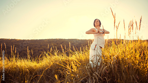 Beautiful pregnant woman doing prenatal yoga on nature outdoors.