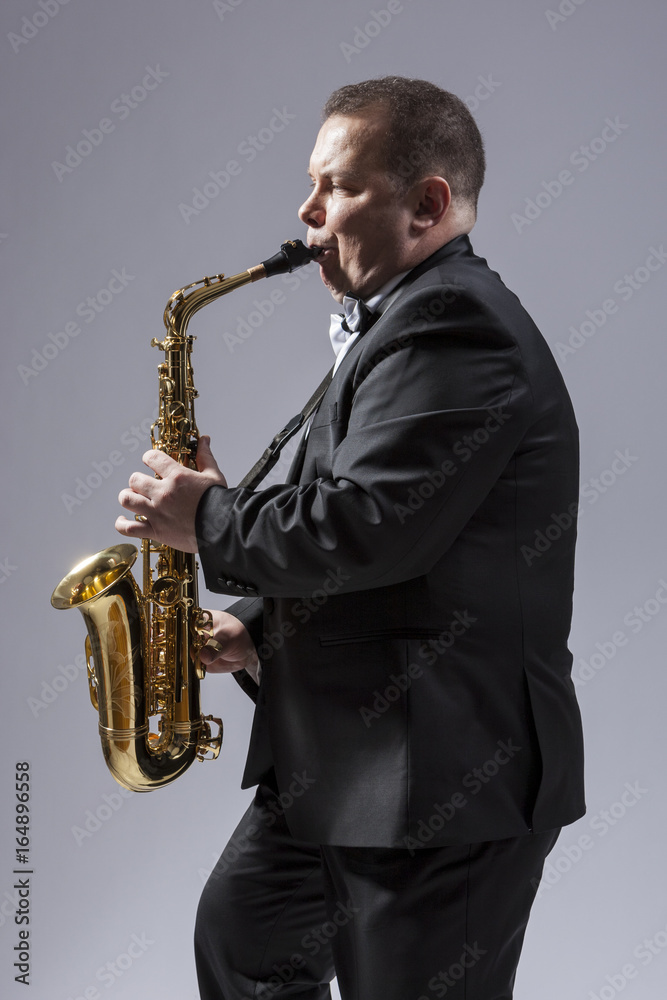 Fototapeta premium Music Concepts. Portrait of Caucasian Mature Concentrated Saxophone Player Playing the Instrument Against White Background.