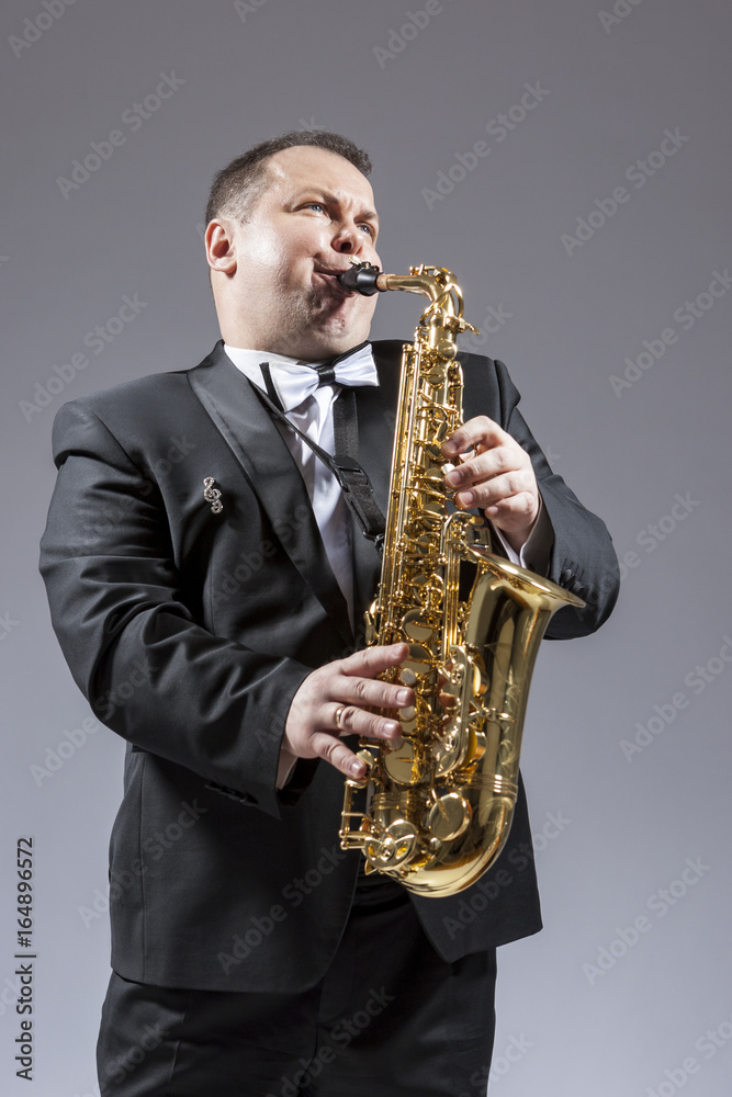 Fototapeta premium Music and Musicians Ideas and Concepts. Portrait of Caucasian Mature Expressive Saxophone Player Playing the Instrument Against White Background.