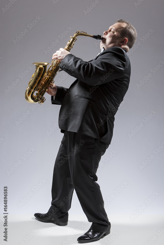 Naklejka premium Music Concepts. Full Length Portrait of Caucasian Mature Concentrated Saxophone Player Playing the Instrument Against White Background.