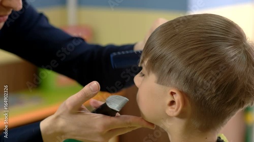 Hairdresser cut bang of the boy with a haircut machine