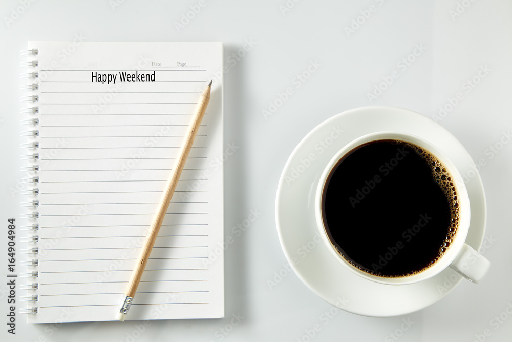 White cup of coffee morning on wooden table with notebook White cup of coffee morning on wooden table with notebook