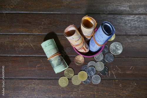 Malaysian Ringgit (MYR) coins and ringgit roll tied with a rubber band on a wooden background.