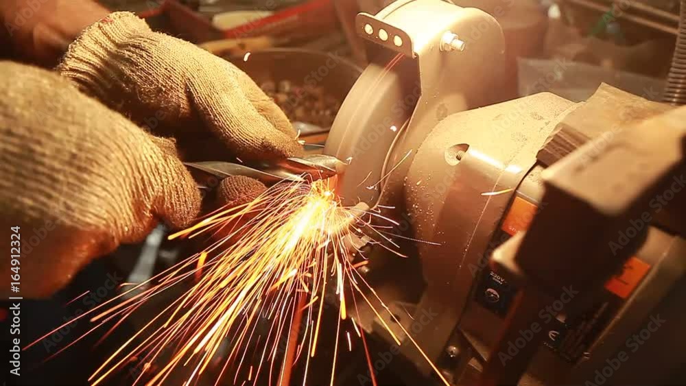 Worker sharpens a drill on a machine