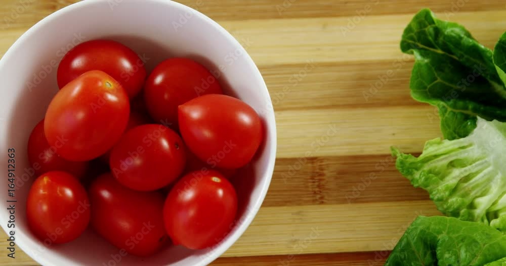 Lettuce and tomatoes in bowl on chopping board Lettuce and tomatoes in bowl on chopping board