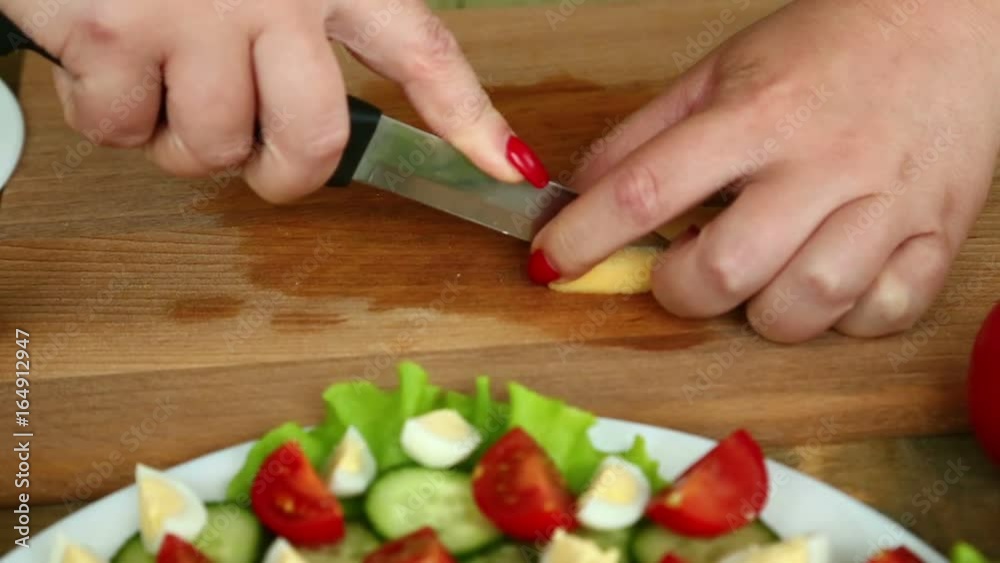 Preparation of homemade vegetable salad with cherry tomatoes, cheese and quail eggs. Female hands cut the cheese with a knife. Camera moves from left to right Preparation of homemade vegetable salad with cherry tomatoes, cheese and quail eggs. Female hands cut the cheese with a knife. Camera moves from left to right