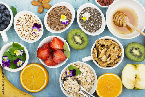 Ingredients for a healthy breakfast, nuts, oatmeal, honey, berries, fruits, blueberry, orange, Edible flowers, Chia seeds, flax seeds, goji berries, almonds walnuts The concept of natural organic food