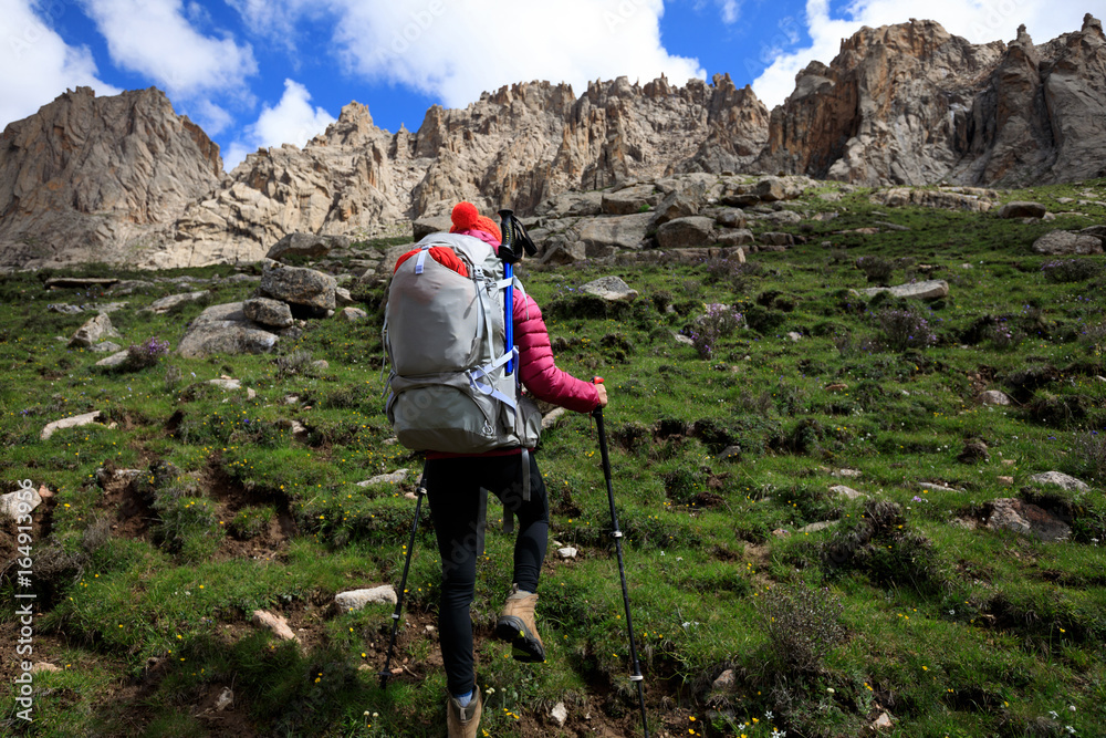 woman with backpack hiking in mountains