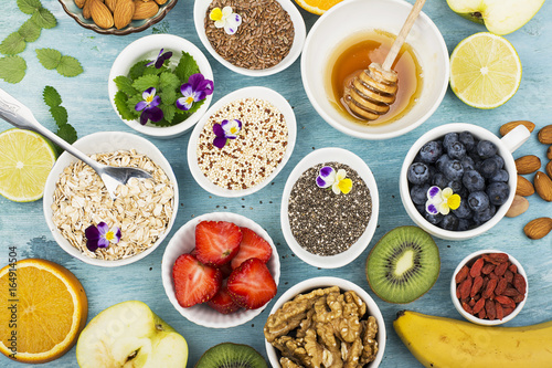 Ingredients for a healthy breakfast, nuts, oatmeal, honey, berries, fruits, blueberry, orange, Edible flowers, Chia seeds, flax seeds, goji berries, almonds, walnuts The concept of natural organic
