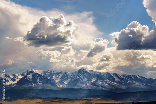 Clouds passing over mountain pinnackle in sunset light in Altai